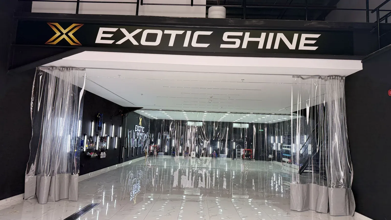 A dust-sealed bay behind strip curtains, under the Exotic Shine sign
